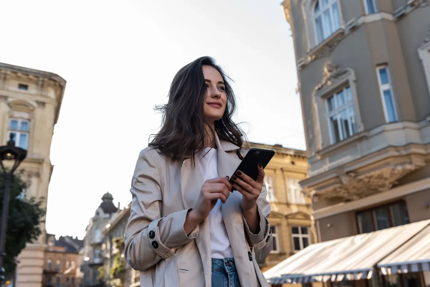 Woman checking her phone on a city street, where most non-broadcast ads must comply with the CAP Code