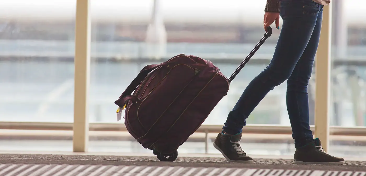 Traveller pulling a suitcase through an airport, the kind of travel insurance ad Voxly Vision checks against ICOBS 2.2