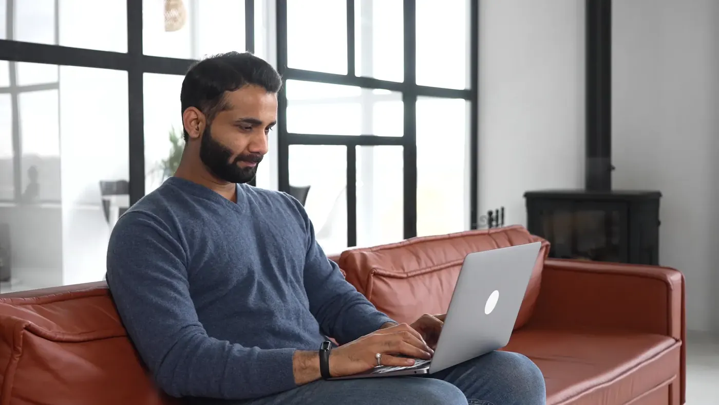 Man browsing on his laptop on the sofa, where online medicine ads must comply with the Human Medicines Regulations 2012