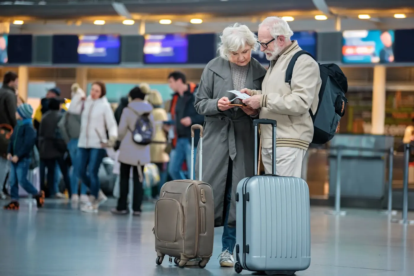 Senior couple with suitcases at the airport, typical later-life mortgage ad imagery checked against MCOB 3A
