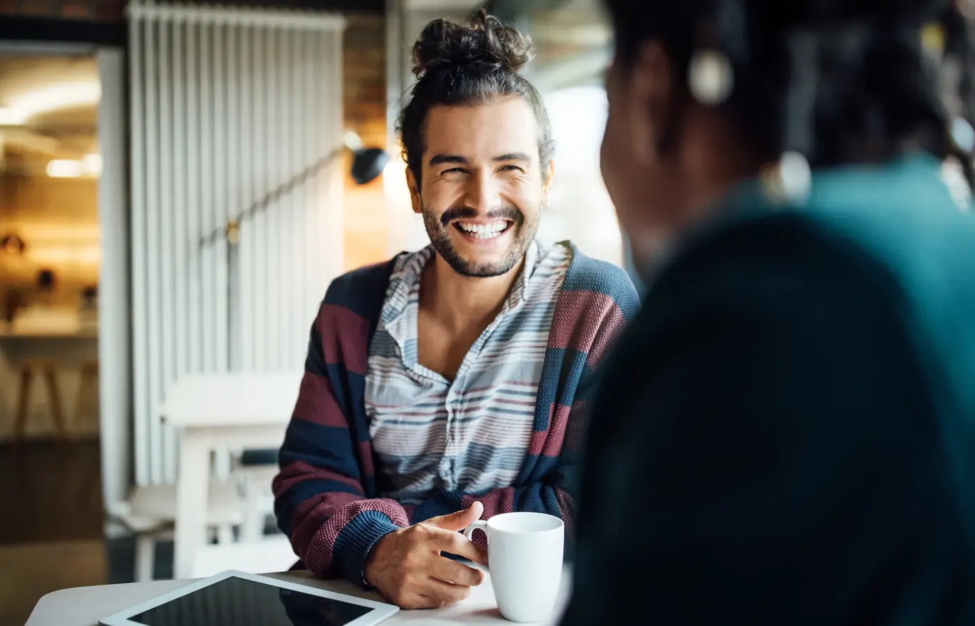 Smiling man in a business meeting at a cafe, discussing marketing claims covered by the Business Protection from Misleading Marketing Regulations 2008