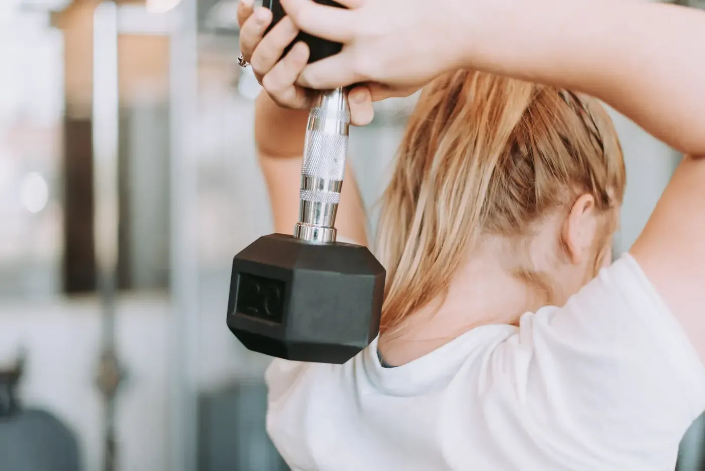 Woman lifting a dumbbell at the gym, typical supplement ad imagery Voxly Vision checks for health claims compliance