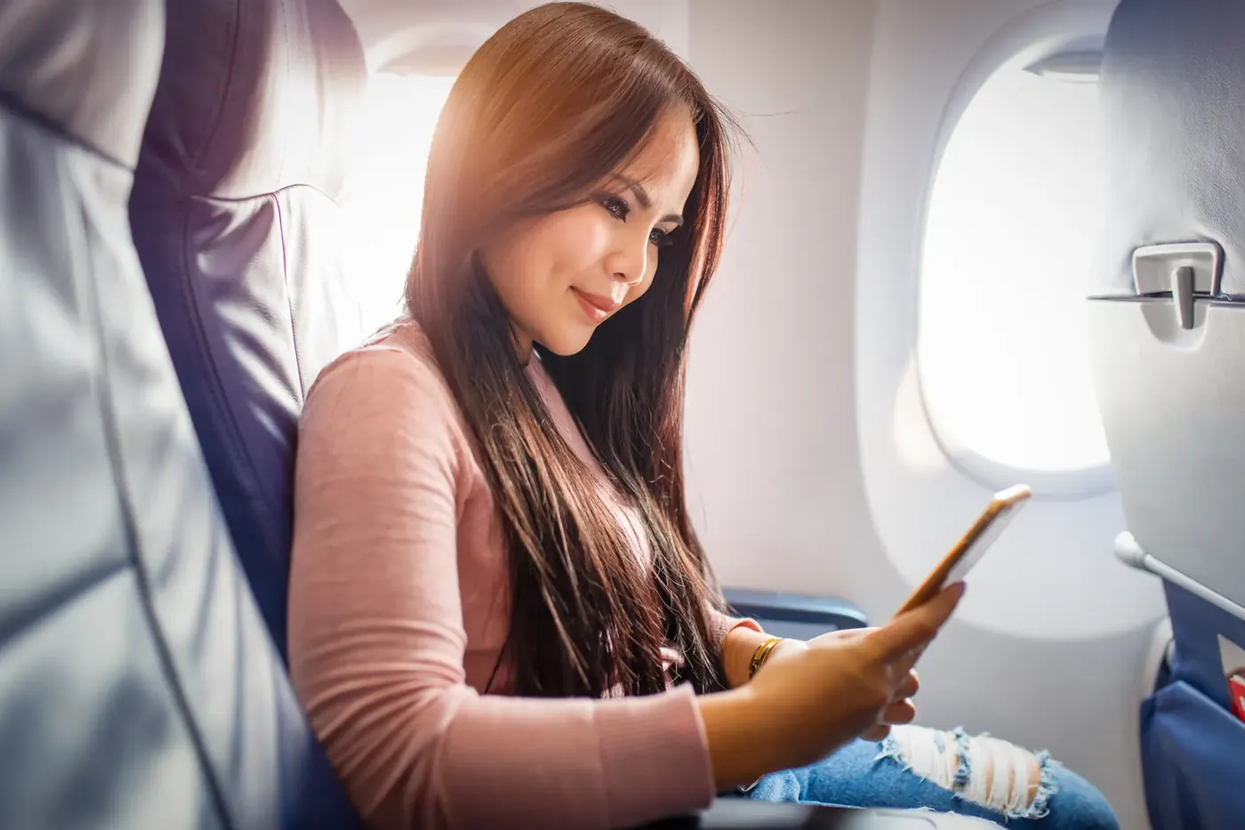 Woman using her phone on a plane, where vape ads must comply with the Tobacco and Related Products Regulations 2016