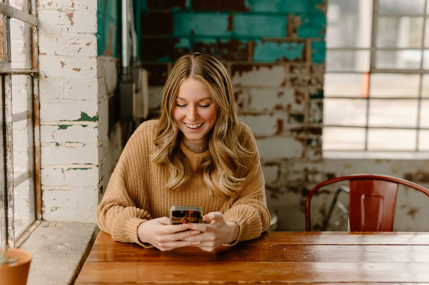 Woman smiling at her phone in a café, scrolling the kind of social ads Voxly Vision checks against the CAP Code and consumer law