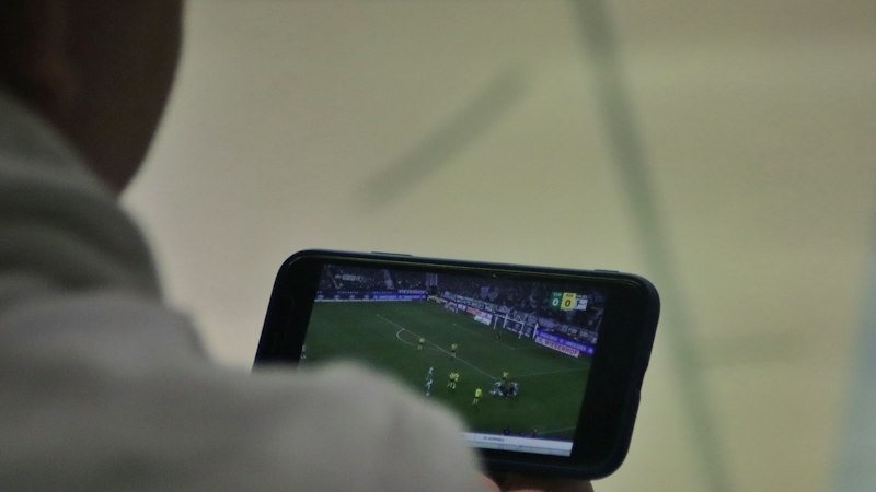 Man watching football on his phone, where Gambling Act advertising rules apply