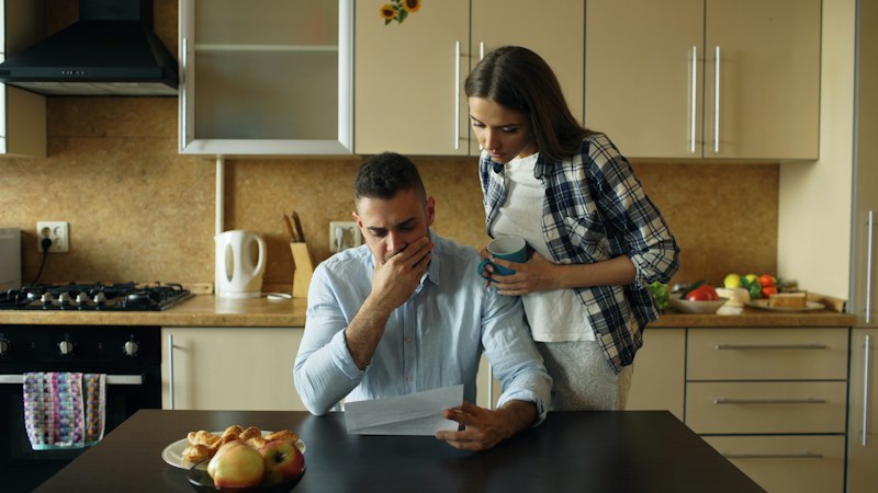 Couple going through bills at the kitchen table, the customers Consumer Duty protects